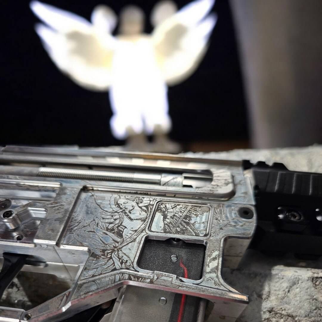 Close-up of custom laser engraved Armoury DSG ARP9 machine pistol with angel statue in the background.