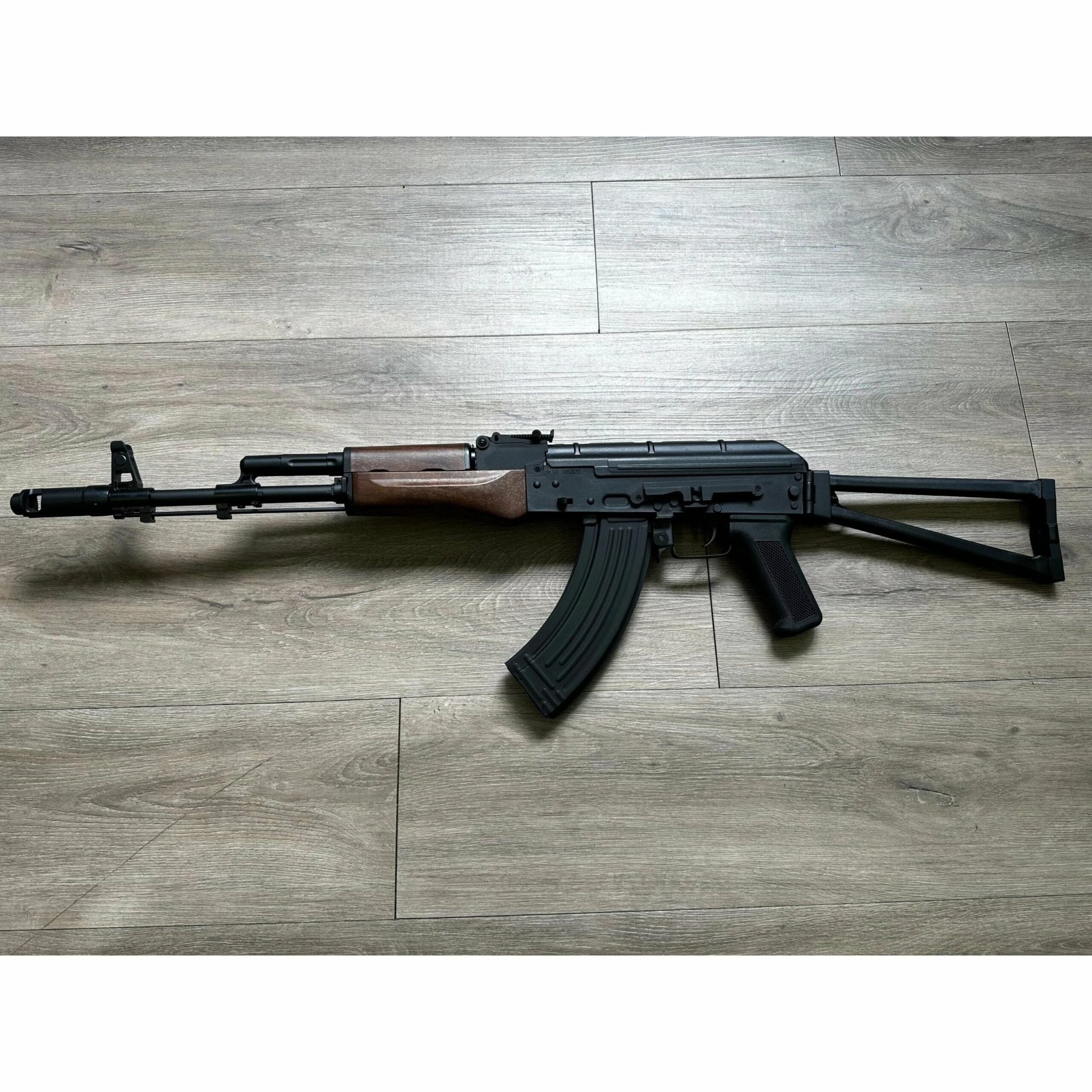 DOUBLE BELL BYP-02B AKS-74N automatic rifle on wooden floor, featuring nylon and metal construction.
